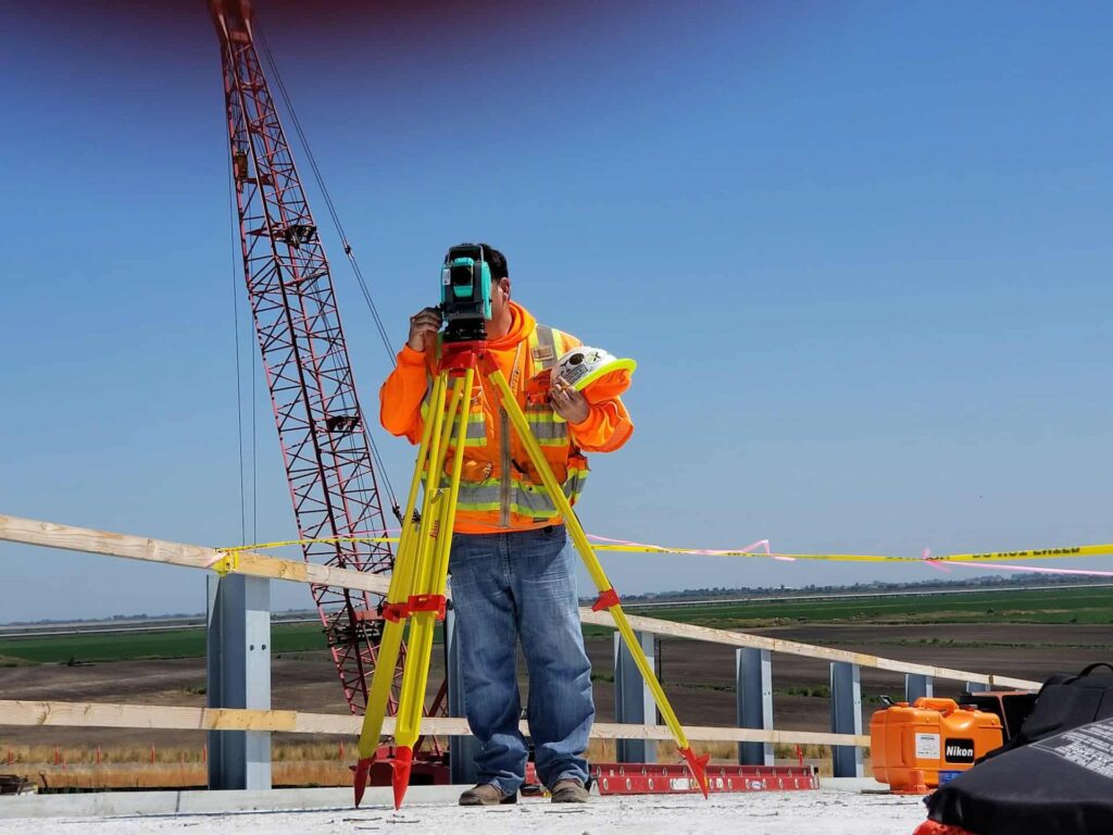 man standing and using measuring level tool on road